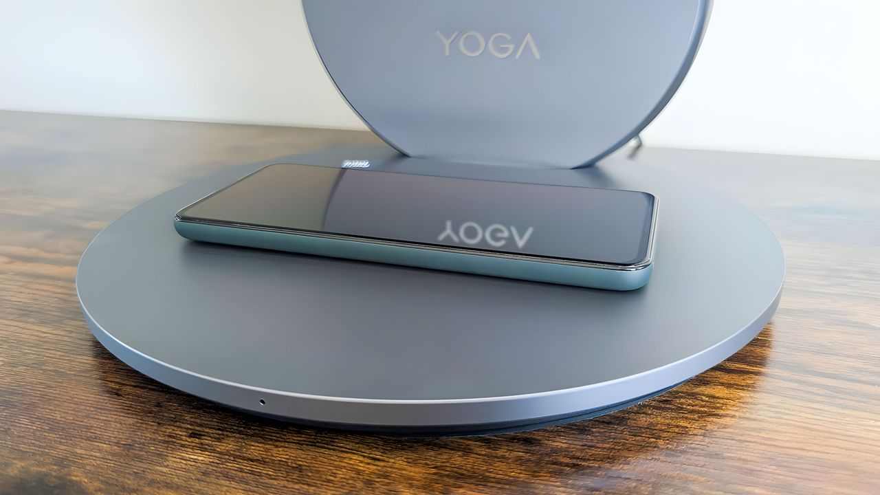 A phone resting on the Lenovo Yoga AIO 27"'s wireless charging base.