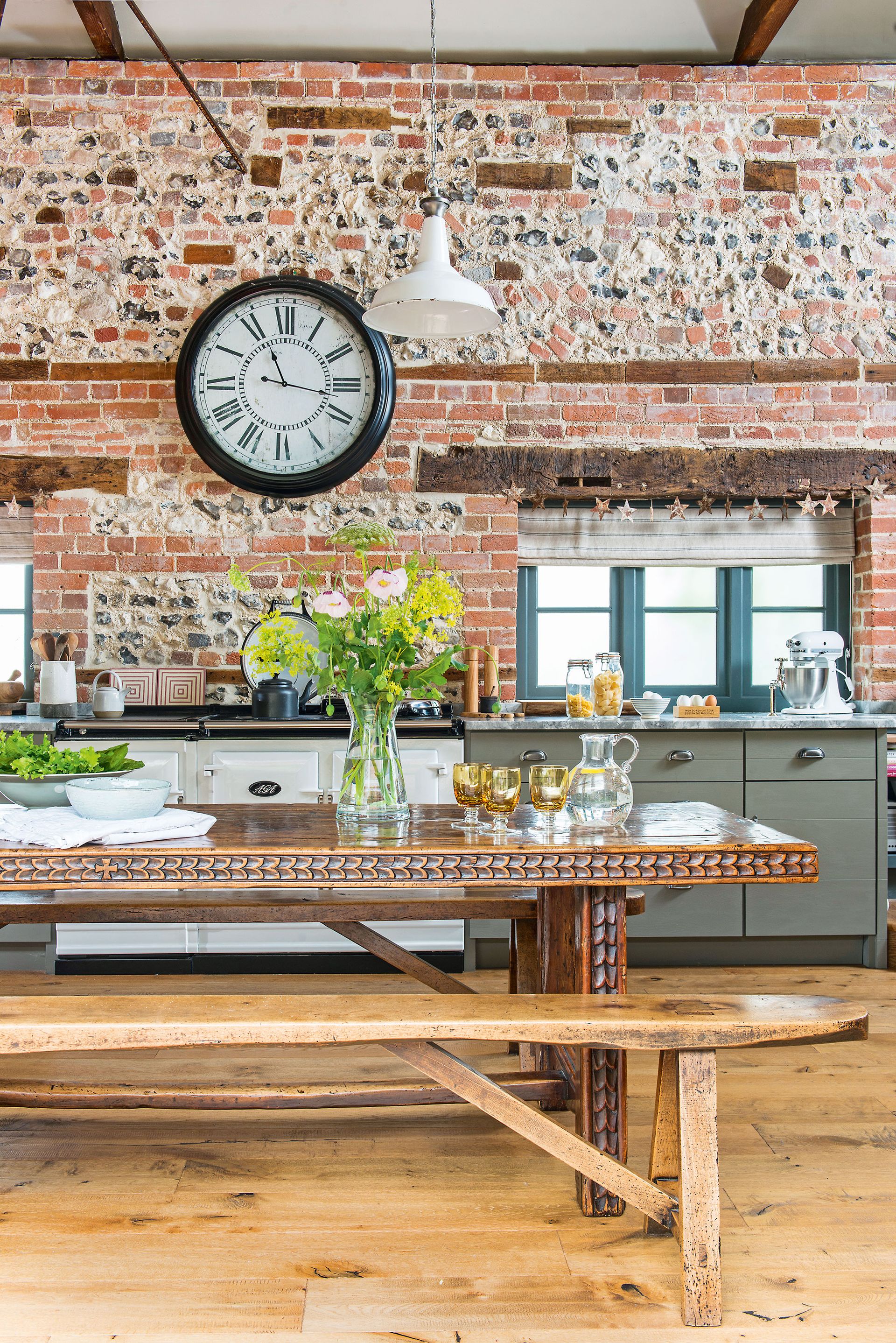dark wood carved antique kitchen table with beams brick wall aga and big clocki