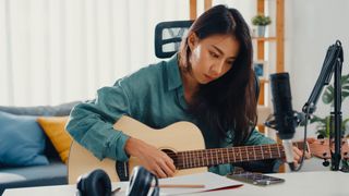 Woman playing acoustic guitar and recording