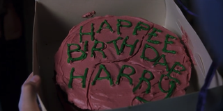 Harry Potter holds a birthday cake, which reads 'Happee Birthdae Harry' in a scene from Harry Potter and the Sorcerer's Stone
