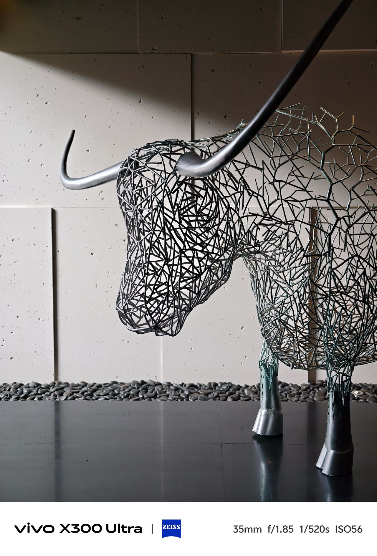 A modern indoor sculpture of a horned bull crafted entirely from interconnected grey metal wires.
