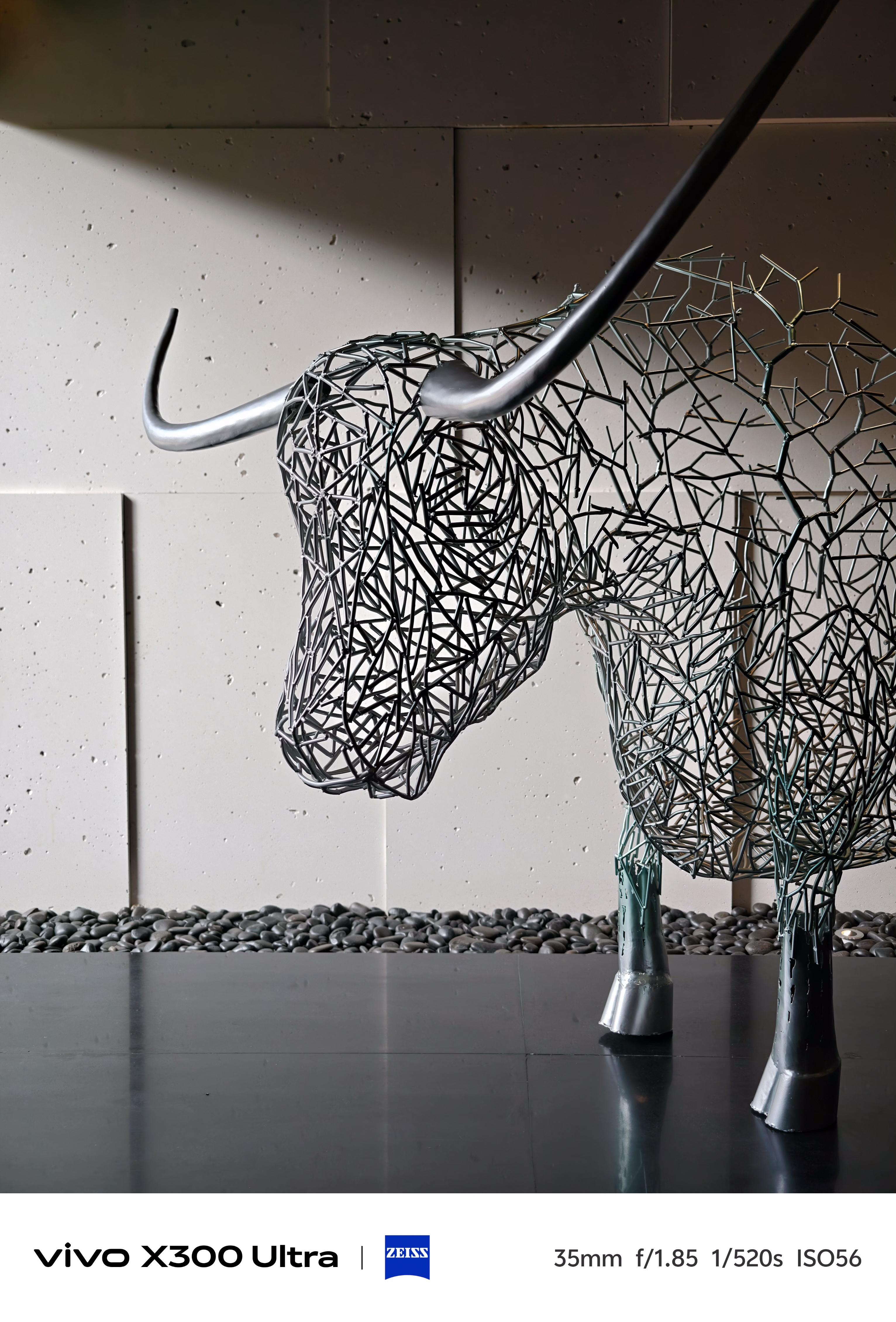 A modern indoor sculpture of a horned bull crafted entirely from interconnected grey metal wires.