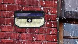 Aootek Solar Outdoor Flood Lights on a wall during rainstorm