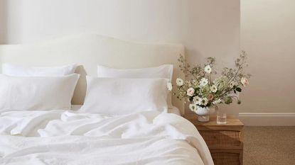 White bed sheets on a bed against a headboard.