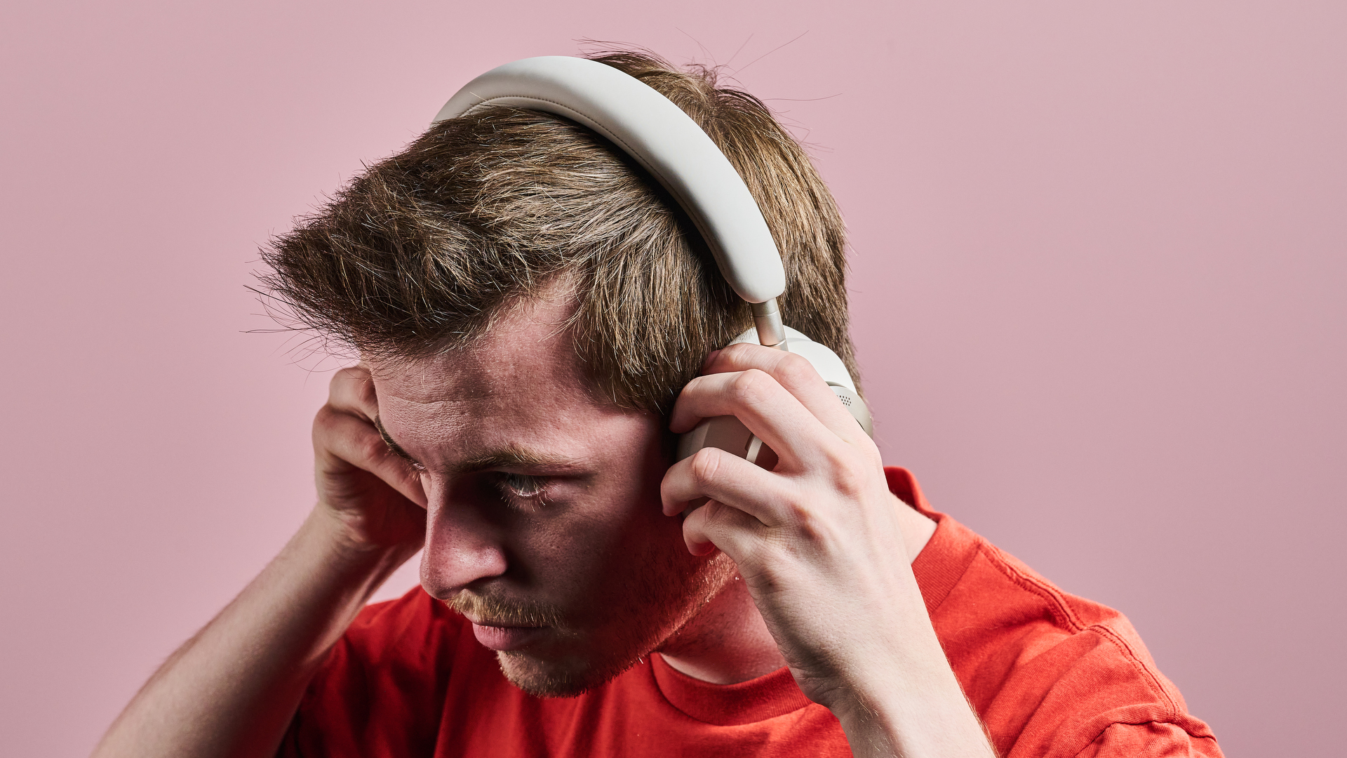 A man putting on the Anker Soundcore Space One Pro in front of a pink wall