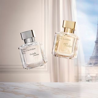 Two Maison Francis Kurkdjian perfume bottles with a blurred background of the Eiffel Tower