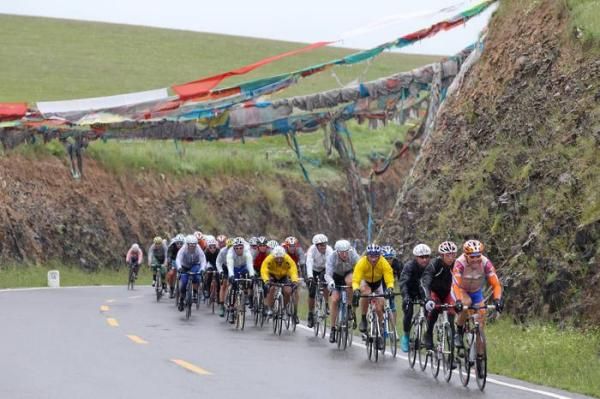 The peloton rides under Tibetan prayer flags.