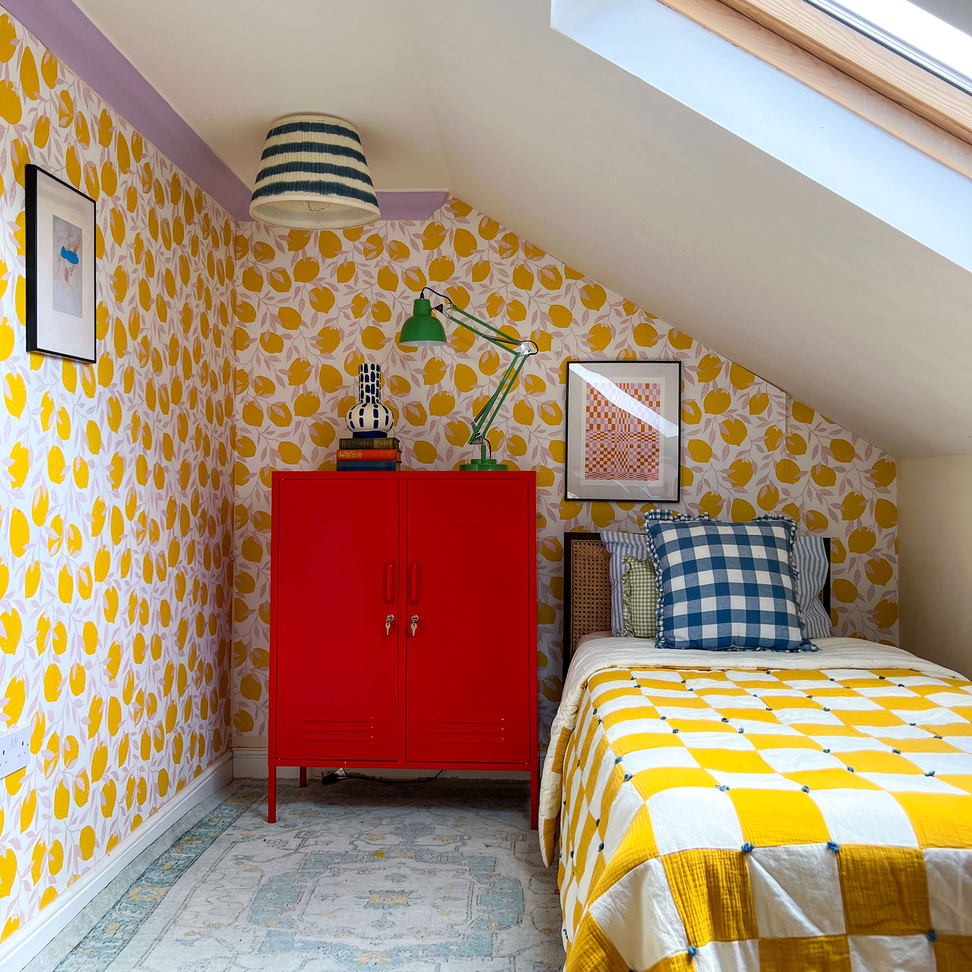 Eaves room with lemon printed wallpaper, red bedside cabinet and yellow and white bedspread