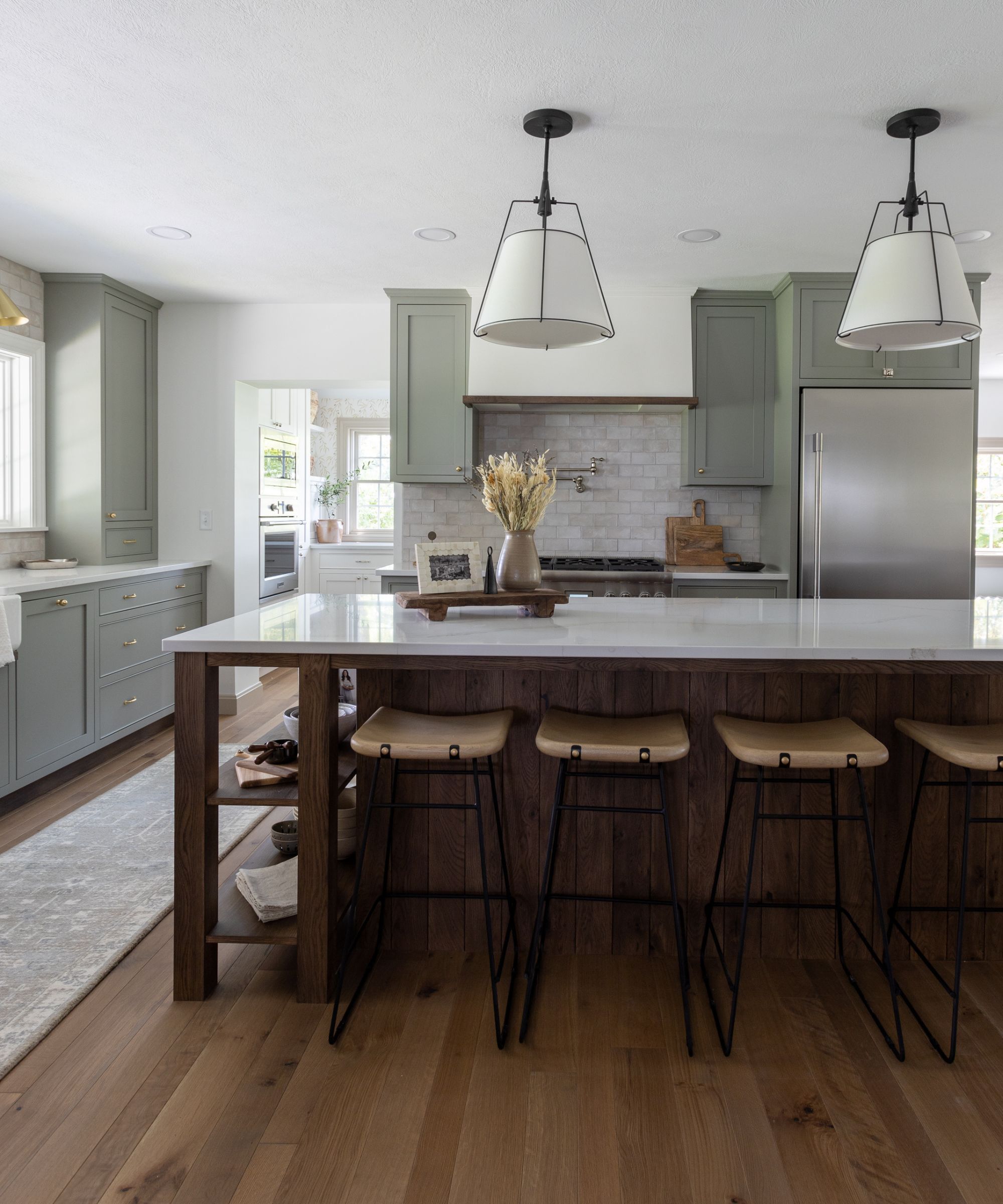 A large kitchen with blue-gray cabinets and a large wooden island