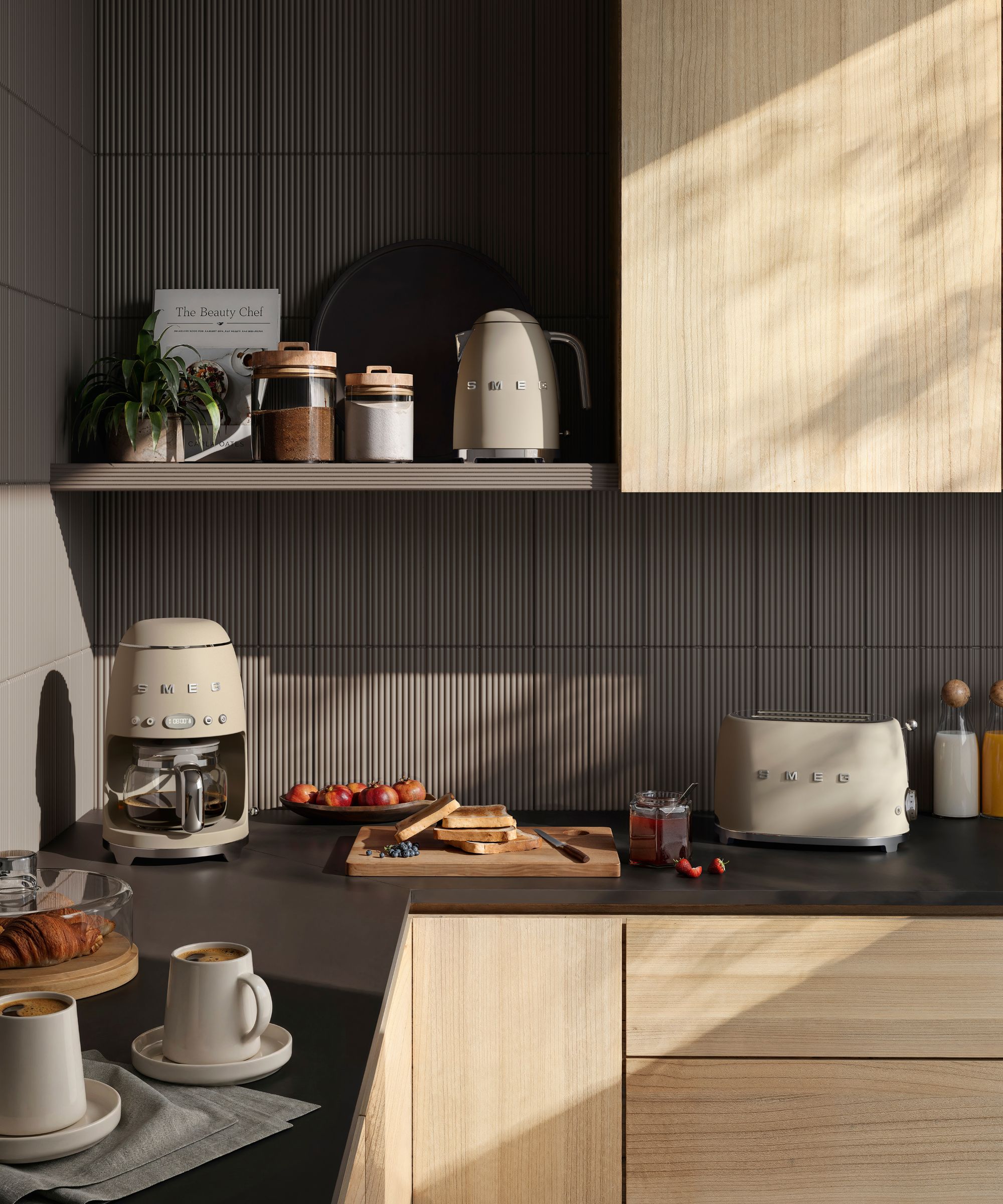 A set of matte cream colored SMEG appliances on a black kitchen counter
