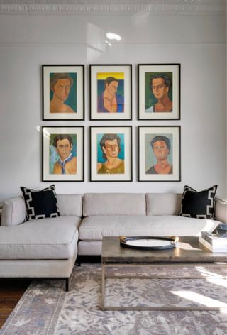 White living room with six framed paintings of different people