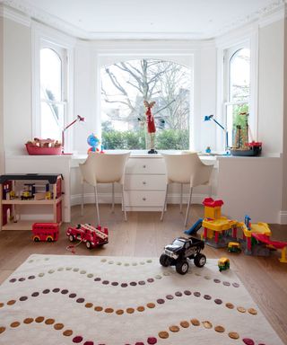 play room with white wall and huge sash window with toys and rug on floor