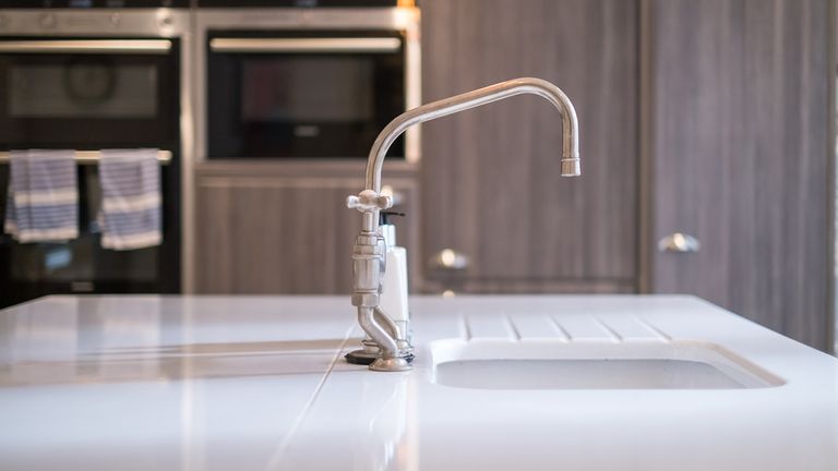 Kitchen sink and silver tap in front of cabinet