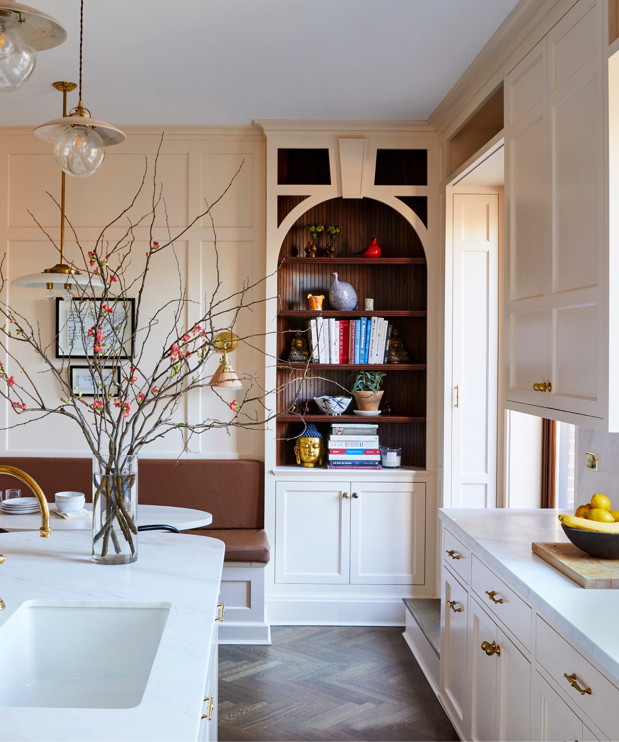 The corner of a New York Brownstone kitchen with pale pink cabinets and an arched open shelving unit