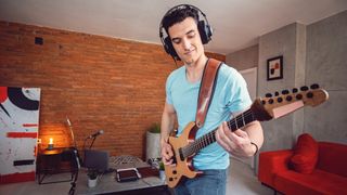 Man plays guitar wearing headphones