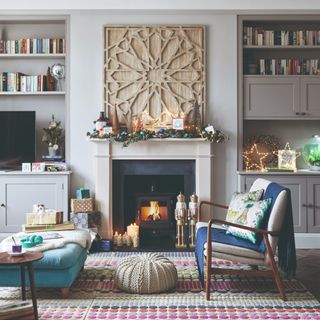 A living room with a fireplace decorated for Christmas with a bench, a pouffe and an ottoman used for extra seating