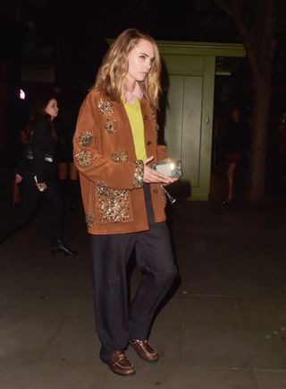 Cara Delevingne wears a brown suede jacket with embellishments for a night out.