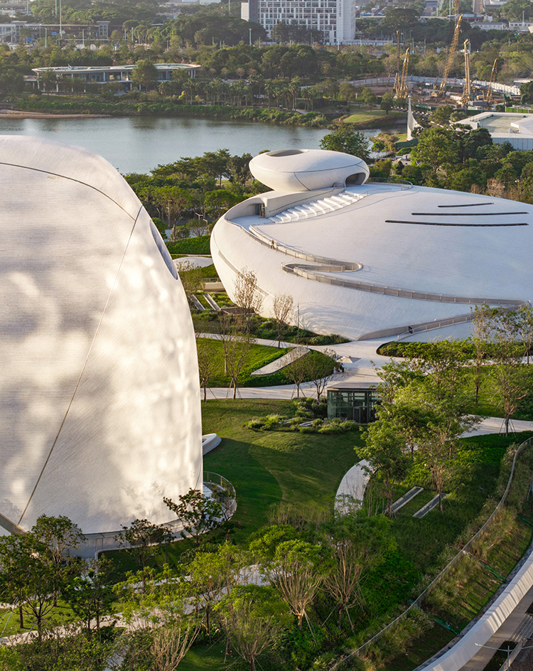 view of MAD Shenzhen Bay Culture Square, all white volumes and curves in a green park