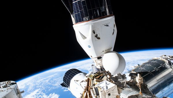 دو سفینه فضایی مخروطی شکل که در پس زمینه زمین به ایستگاه فضایی بین المللی متصل شده اند