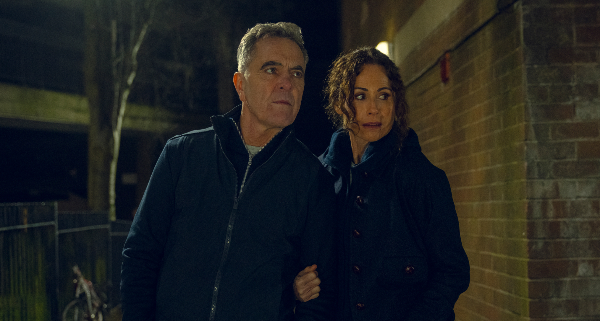 james nesbitt as simon and minnie driver as ingrid wearing all black sneaking around a building investigating in a scene from harlan coben's run away