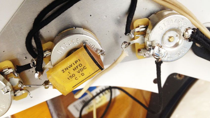 A peek under the pickguard reveals vintage-style components, but modern wiring
