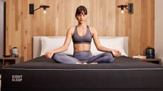 A woman sitting on the Eight Sleep Pod mattress and meditating