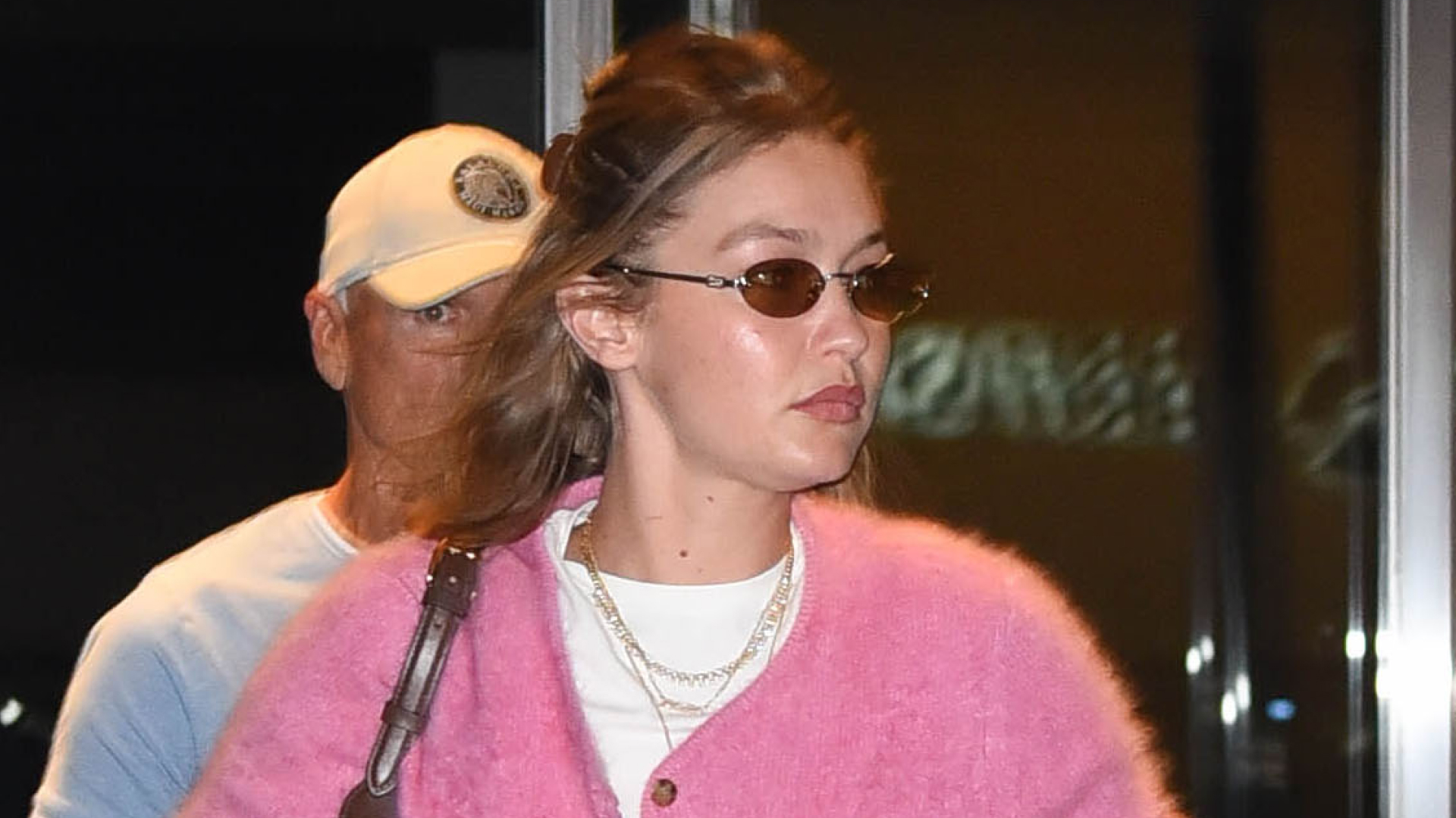 Gigi Hadid arrives at airport wearing a pink cardigan, white T-shirt, faded jeans, brown loafers and white socks