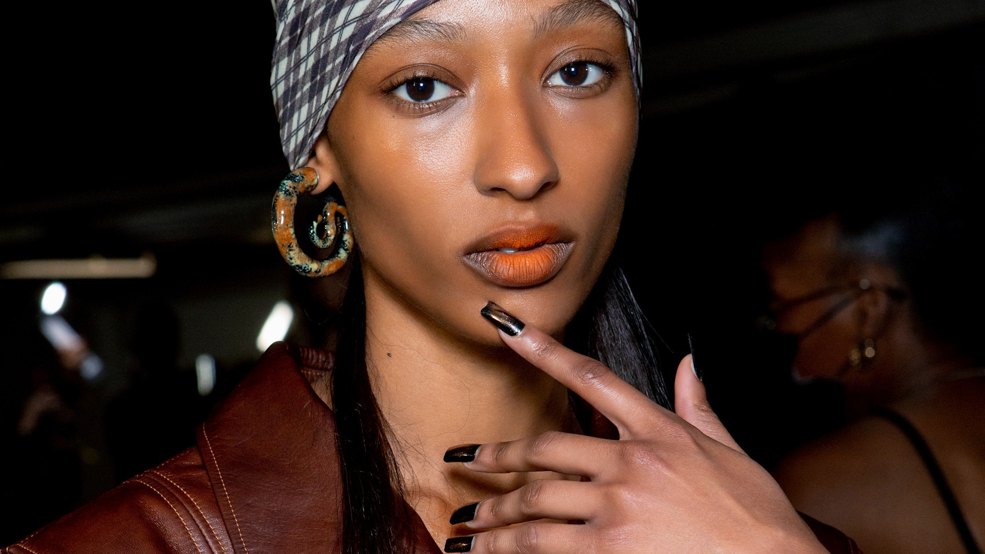 woman with a brown manicure and orange lipstick