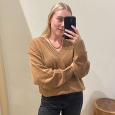 Woman wears camel v-neck cashmere sweater and black jeans