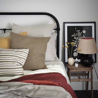 Nate Berkus and Jeremiah Brent bedroom design tips: black wrought iron bed with neutral plain linen and white walls