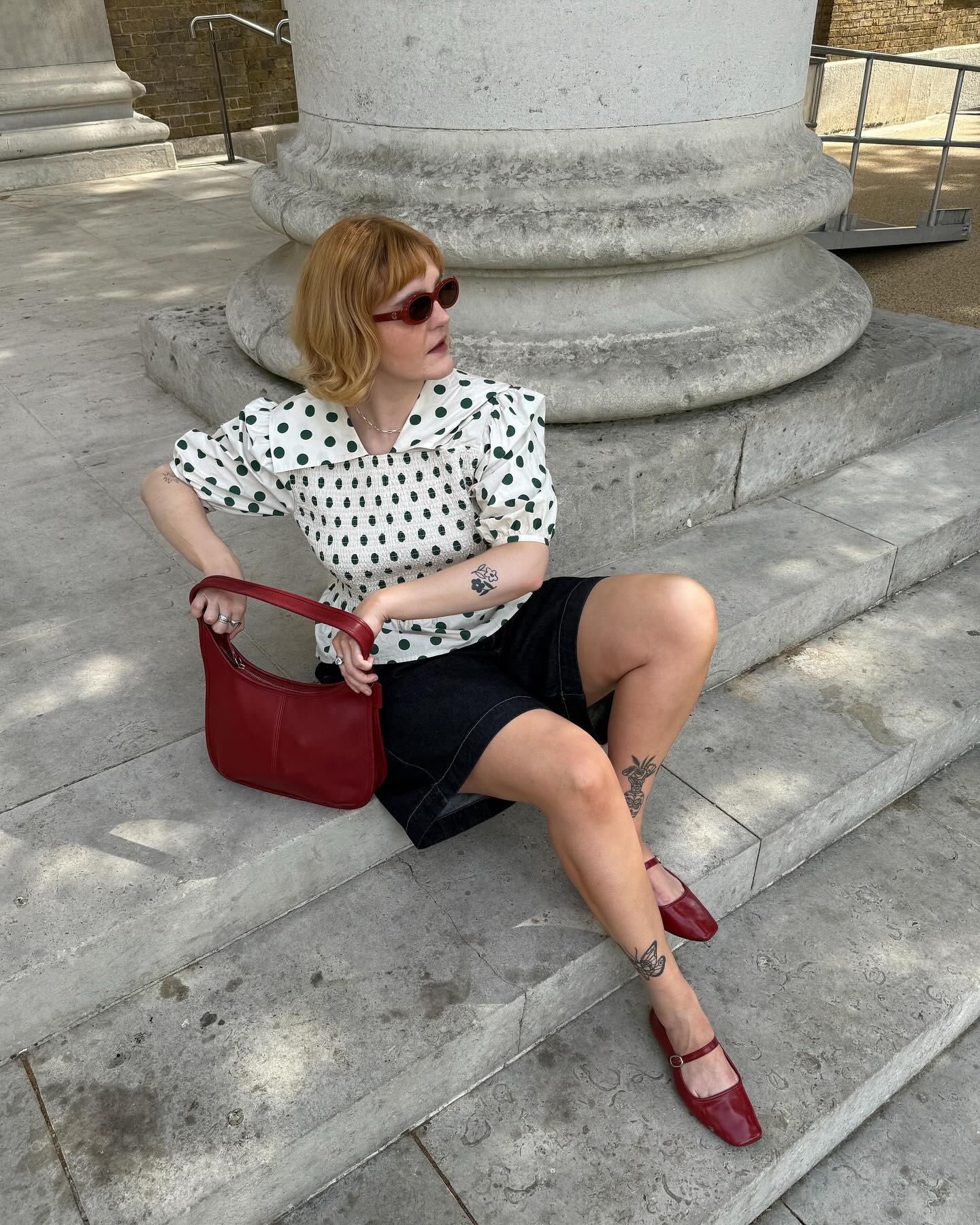 Influencer wears the Shrimps Rowan blouse with dark wash denim shorts and red leather mary janes.