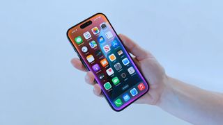 Close up of an iPhone in someone&#039;s hand with the Siri screen border activated in iOS 18