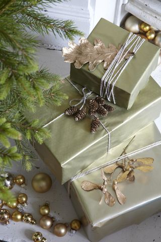 Gold wrapped Christmas gifts decorated with sprayed pine cone decorations