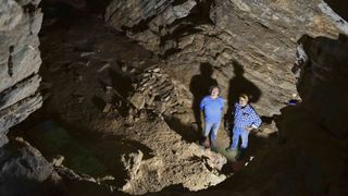 Two men stand in a cave