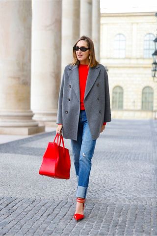 a street style influencer wearing straight leg jeans with red accessories