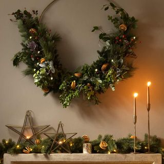 Mantelpiece dressed for Christmas with candles and wreath, with gold candles and gold star decorations