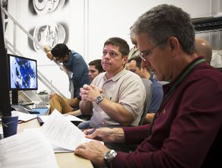 Commercial crew astronaut Bob Behnken, center, watches during an evaluation visit for the Crew Dragon spacecraft at SpaceX's Hawthorne, California, headquarters as former astronaut Mike Good, right, looks on.