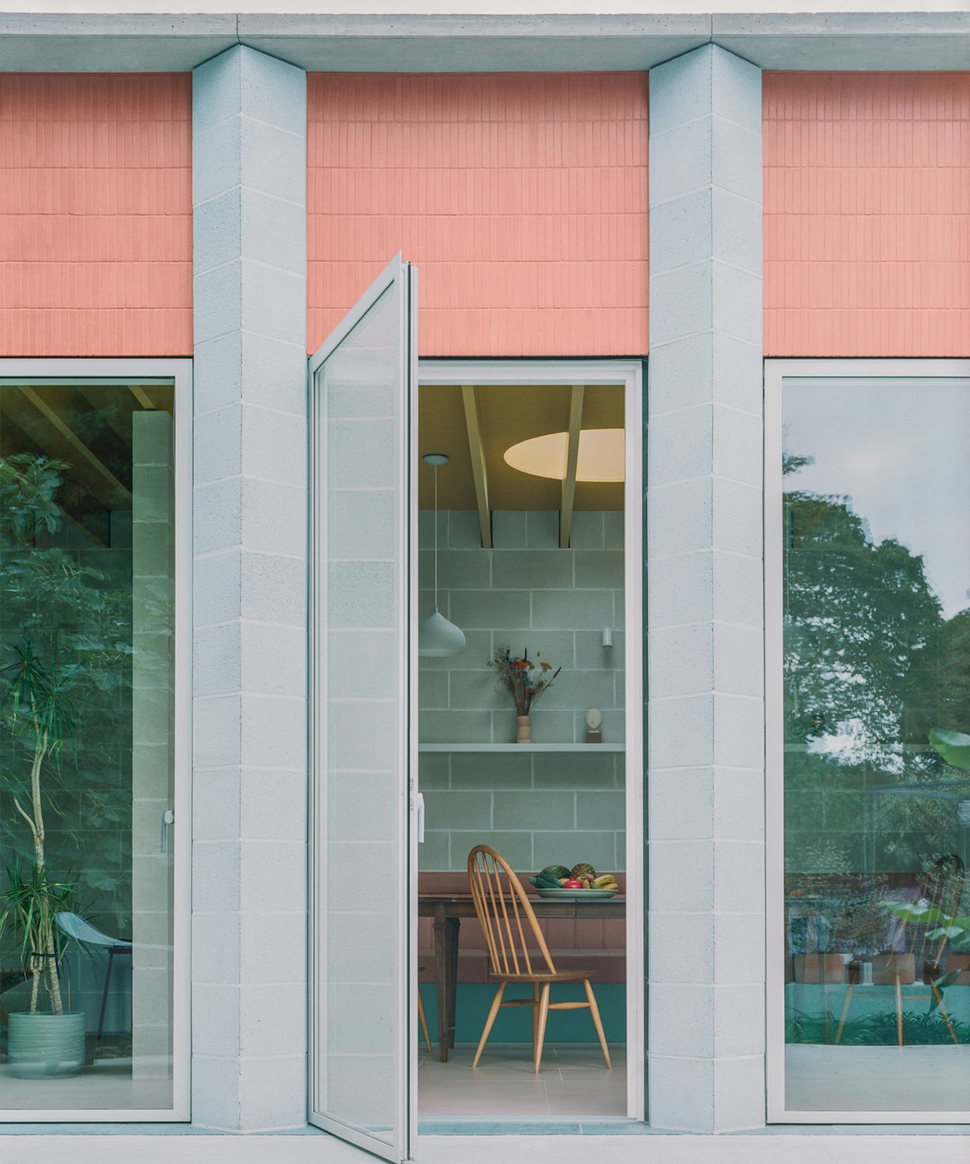 An extension with a glass door next to a blue column with terracotta tiles