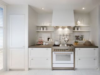 white kitchen with large storage units and stove by steel