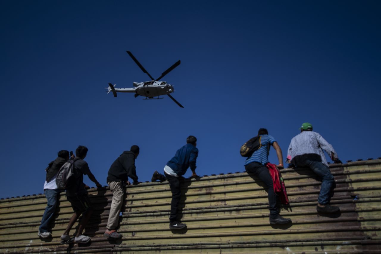 Migrants try to climb a fence on the border