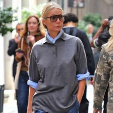 Gwyneth Paltrow wears a gray polo sweater over a blue button up.
