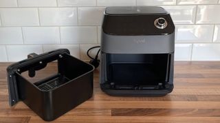 The Kyvol AF600 Air Fryer on a kitchen countertop with the frying basket removed and positioned to the left hand-side