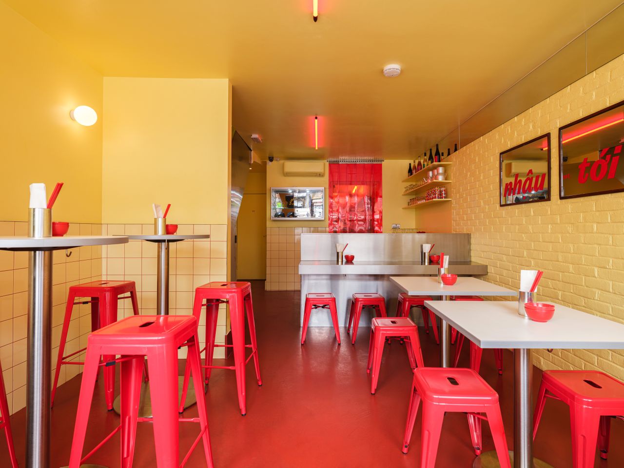 A butter and red-drenched restaurant's dining room mixes tiled, brick, and stainless steel surfaces to a captivating effect.