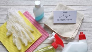 A bottle of hydrogen peroxide next to cloths and gloves