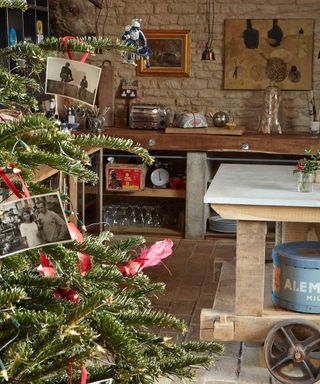 a wooden rustic country kitchen with a real christmas tree decorated with old black and white photos