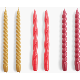 six twisted candles in different shapes and shades of red and yellow
