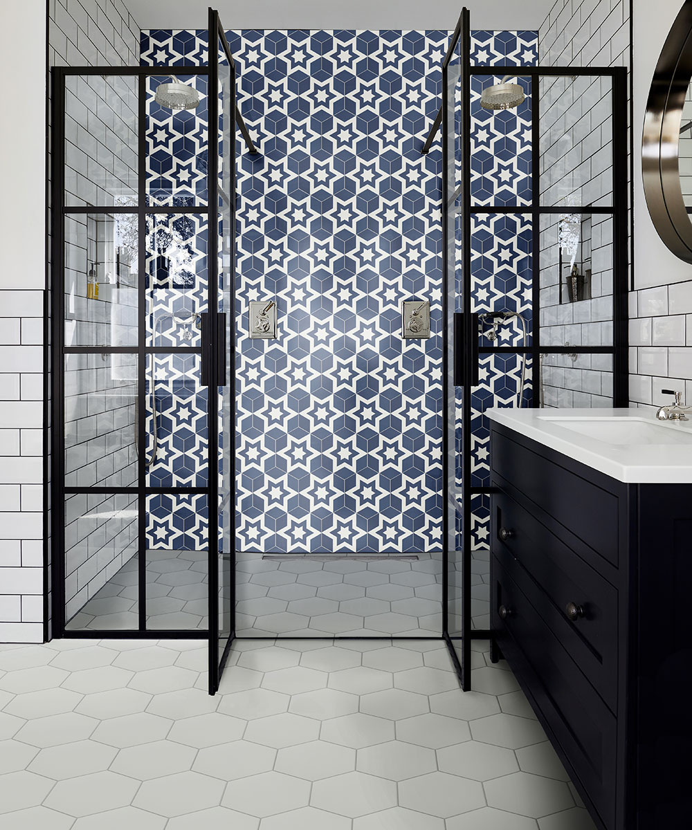 A walk-in shower with a patterned tiled wall