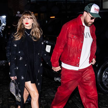 Taylor Swift in a long, crystal-embellished black coat and Travis Kelce, wearing red pants and a matching red jacket, while out in New York City on December 28, 2024