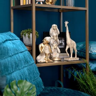 Blue chair in front of blue wall with bookshelf with ornaments