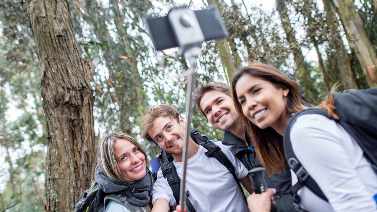 People in forest taking picture using selfie stick